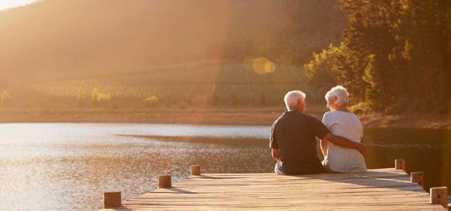 retired couple sitting in sunset on a dock